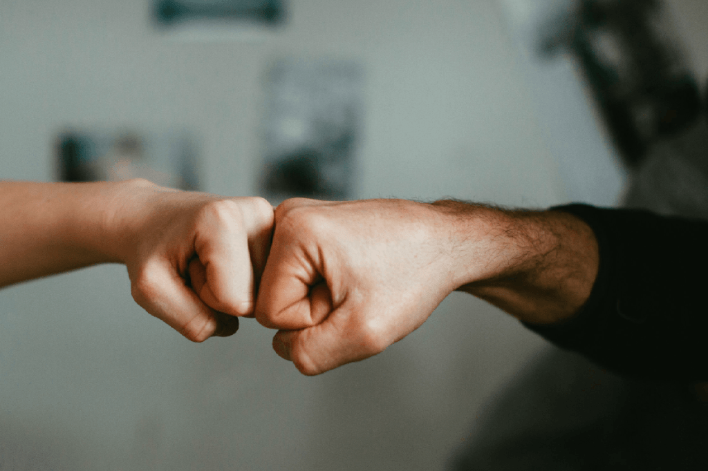 Two hands of two persons doing a fistpump.